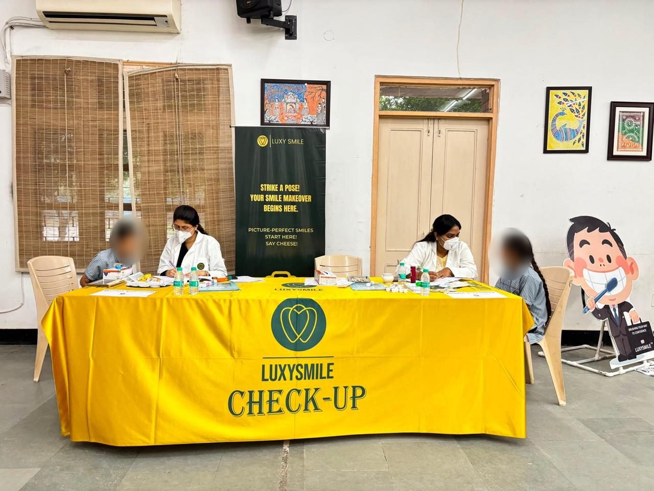 Two dental professionals screening students at a LuxySmile check-up table