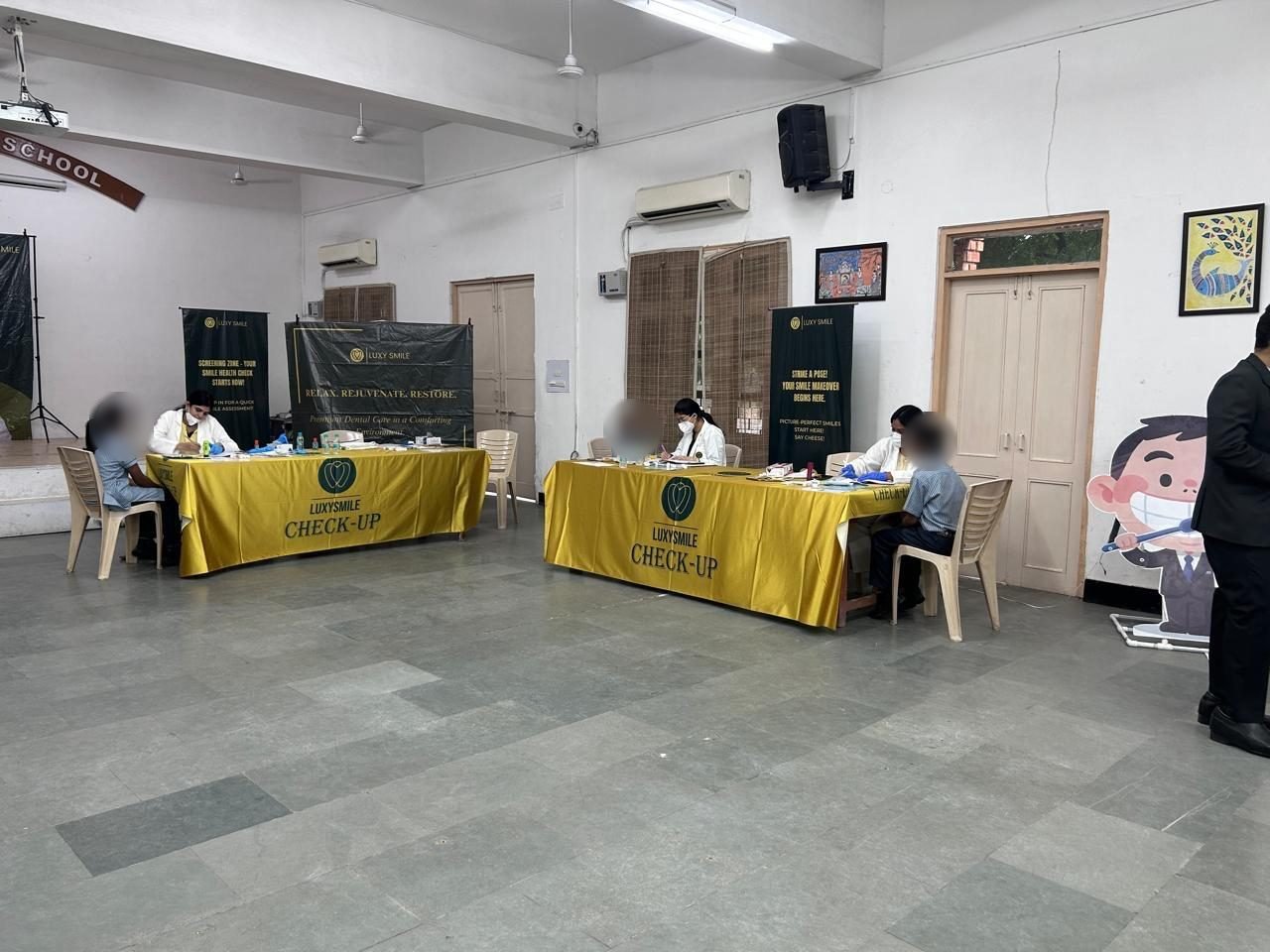 Dental professionals at LuxySmile check-up tables in a school hall