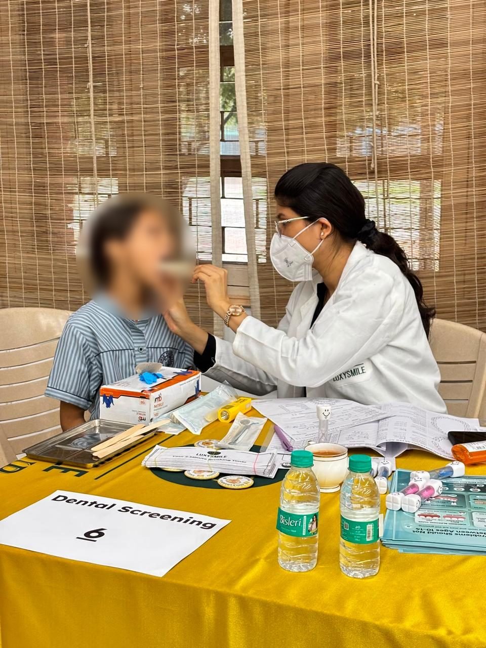 A dental professional examining a student during in-school LuxySmile screening