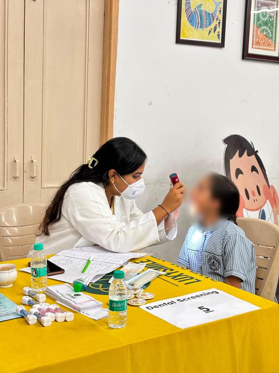 A dental professional screening a student at a LuxySmile check-up table